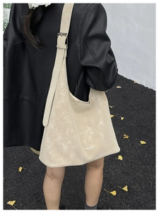Detailed back view of a beige large tote bag on a model in a minimalist outdoor setting