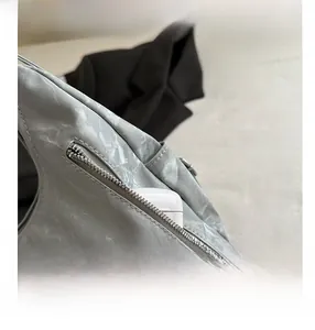 Detail view of the side zipper pocket and wrinkled texture on a grey tote bag