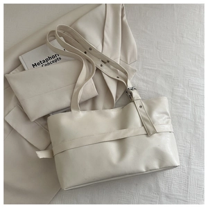Detailed macro view of the cream leather tote bag with adjustable straps and metal rivets