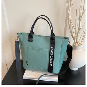 Close-up of a mint green tote lunch bag with adjustable shoulder straps and front pocket