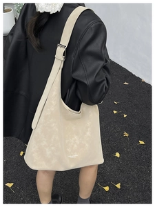Detail of off-white oversized hobo bag with wide strap and retro textured leather finish