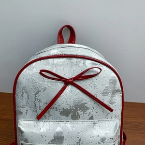 Detail of silver butterfly pattern backpack with red leather trim and red bow accent