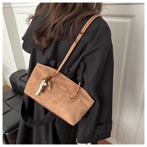 Detailed view of brown suede shoulder bag with beaded charm and Fashion emblem