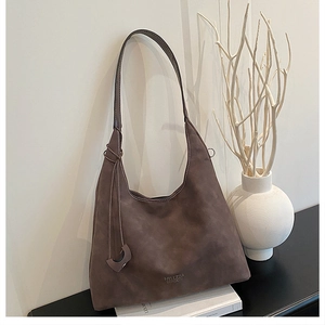 Dettaglio borsa hobo in pelle opaca marrone scuro con logo in un ambiente minimalista