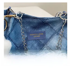 Detail of blue denim quilted tote bag featuring silver chain and fuzzy pompom charm
