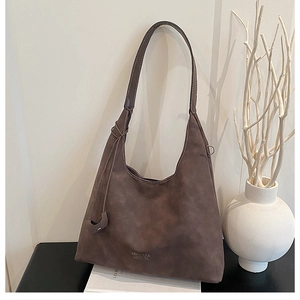 Dettaglio di una borsa tote in pelle scamosciata marrone con logo HYLLZZA LONDON e lacci