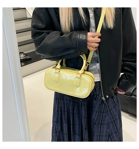 Detail of bright yellow patent leather pillow bag with glossy finish and gold-tone hardware