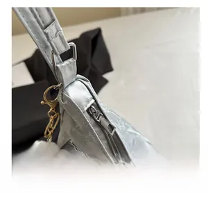 Macro detail of smooth silver-gray textured bag zipper with fluffy white ball charm