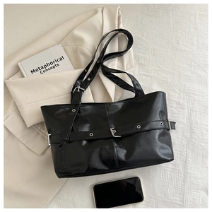 Detailed overhead view of black leather tote bag with decorative buckle and metal eyelets