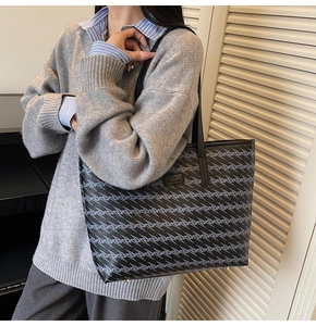 Close-up of geometric pattern on large tote bag with metallic feet and logo detail