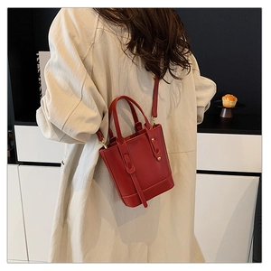 Close-up of a red leather bucket bag with top handles and adjustable shoulder strap