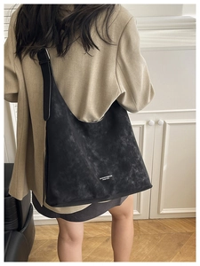 Detail of a large black faux suede tote bag showing the text print and spacious design