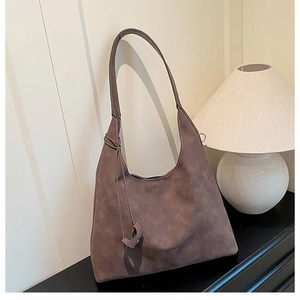 Dettaglio di una borsa tote in pelle scamosciata marrone scuro con logo dorato