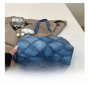 Close-up of blue quilted denim tote bag with chain strap and plush cloud charm detail