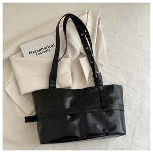 Detail of adjustable shoulder strap with metal eyelets on a black leather tote bag