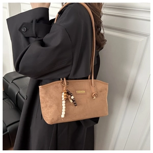 Brown suede tote bag side view on model featuring chic knotted straps and wooden bead charm