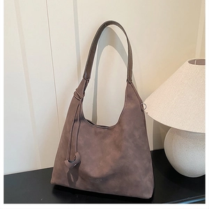 Dettaglio di una borsa tote vintage in pelle scamosciata marrone con tracolla sottile