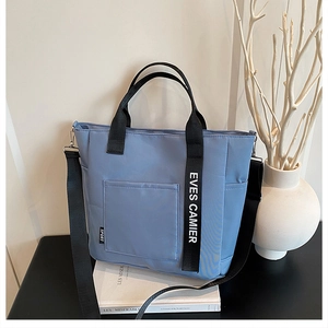 Detail of blue nylon lunch tote featuring adjustable black shoulder strap and top handles