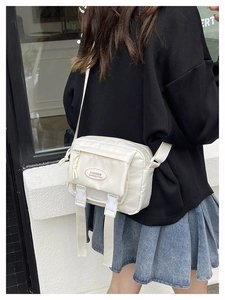 Beige nylon crossbody bag detail with double buckle closures and adjustable shoulder strap