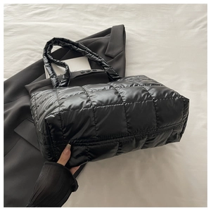 Close-up of a black quilted tote bag with square stitching and soft padded texture