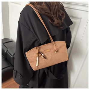 Detailed view of brown suede tote bag with wooden bead charm and FASHION label