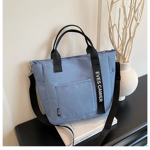 Detail of blue canvas lunch bag featuring high-density nylon strap and front pocket