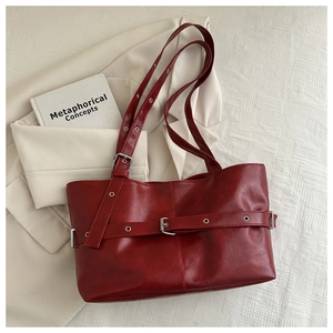 Detail of burgundy tote bag showing glossy leather texture and silver buckle accents