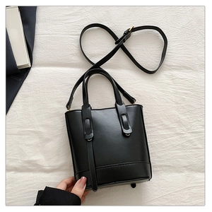 Vue de dessus d'un sac seau en cuir noir avec détails dorés et bandoulière
