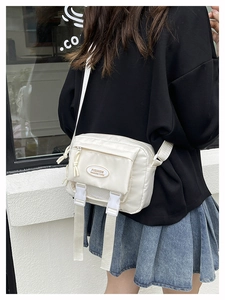 White nylon messenger bag featuring front buckle straps and fashion logo detail
