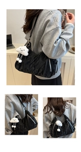 Detailed texture of black pleated tote bag with silver zipper and plush cloud charm