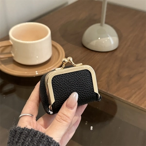 Mini black lychee leather jewelry pouch with gold kiss-lock closure held in hand