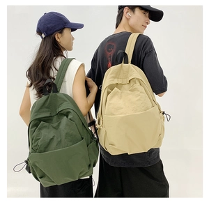 Detail of minimalist large capacity backpacks in green and khaki with drawstring accents