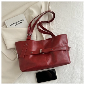 Detail of dark red tote bag with silver metal eyelets and soft synthetic leather texture
