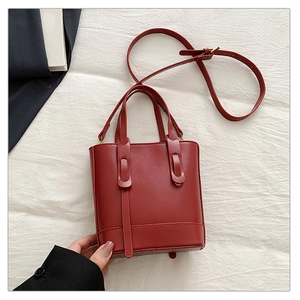 Détail du sac seau rouge foncé avec coutures renforcées et bandoulière réglable