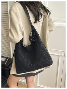 Close-up of black textured tote bag featuring white brand logo and wide shoulder strap