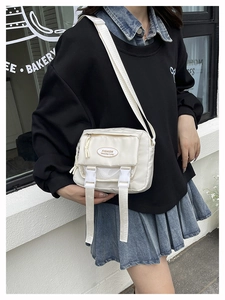 Close-up of a white Japanese style nylon messenger bag with flap buckles and adjustable strap