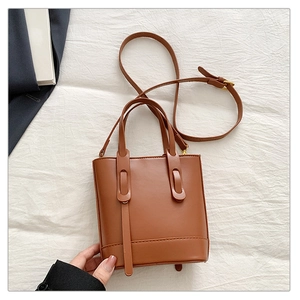 Détail d'un sac seau en cuir marron avec coutures renforcées et bandoulière réglable