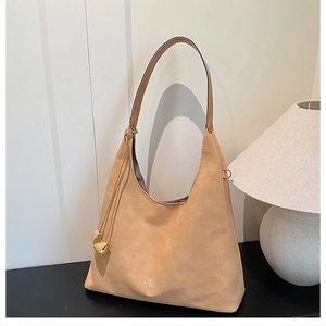 Dettaglio della borsa tote in pelle scamosciata beige con logo e ciondolo metallico