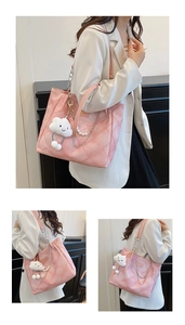 Detailed close-up of pink quilted tote bag with pearl chain and cloud plush charm