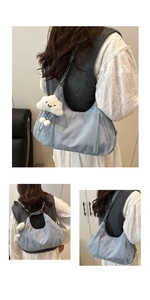 Detailed view of light blue crescent bag with metal zippers and a cloud plush charm