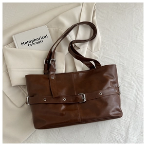 Detail of dark brown wax leather tote bag with silver buckle and eyelet strap decoration