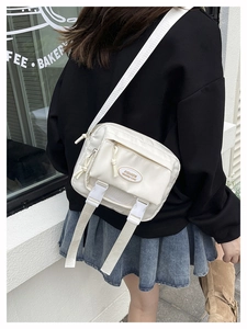 Detail of white nylon messenger bag showing utility straps and plastic buckle closure