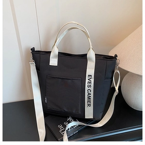 Detail of black nylon lunch tote bag with white adjustable strap and front pocket