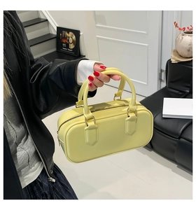 Close-up of yellow PVC jelly cylinder bag featuring golden zippers and handle details