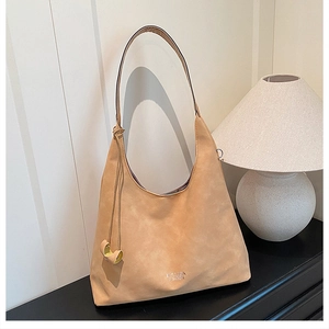 Primo piano di una grande borsa hobo in pelle scamosciata kaki con dettagli di nappe decorative
