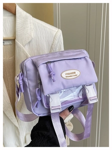 Detail of lavender nylon crossbody bag with dual white buckles and mesh pocket