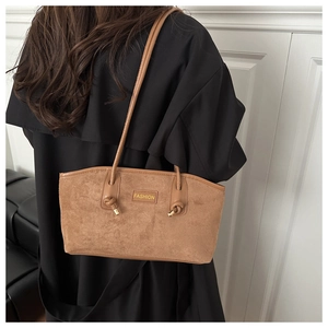 Detail of brown suede tote bag featuring fashion tag and gold metal knot strap details
