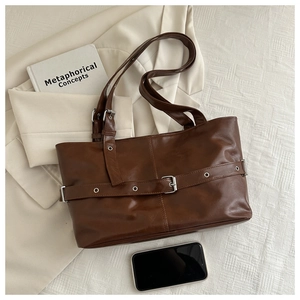 Detail of dark brown leather tote bag featuring decorative buckle and silver hardware
