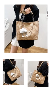 Detail of khaki quilted tote bag with chain strap and plush cloud charm accessory