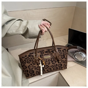 Detail of leopard print tote bag with brown leather handles and wooden bead tassel